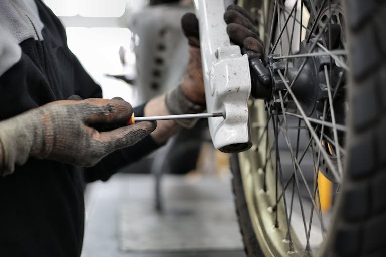 person holding screwdriver upon e-bike rear wheel