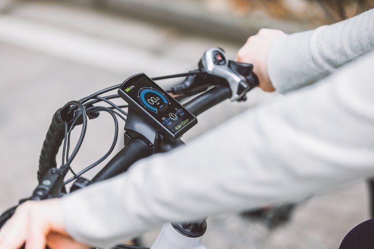 Man handling e-bike while his battery meter shows fully charged battery.